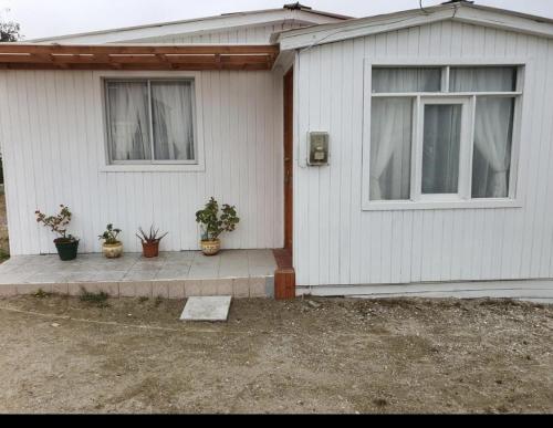 Casa blanca con 2 ventanas y macetas en Casa Quelita, en Punta de Choros