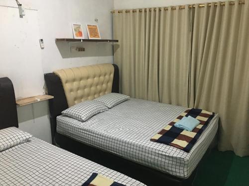 a bedroom with two beds and a window with curtains at LORENT HOSTEL in Kampungdurian
