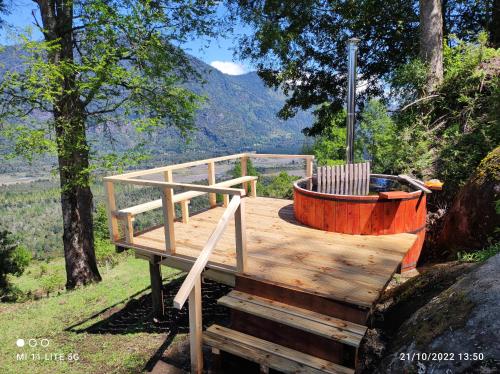 una terraza de madera con bañera de hidromasaje en el bosque en cabaña vista nilahue, en Ranco