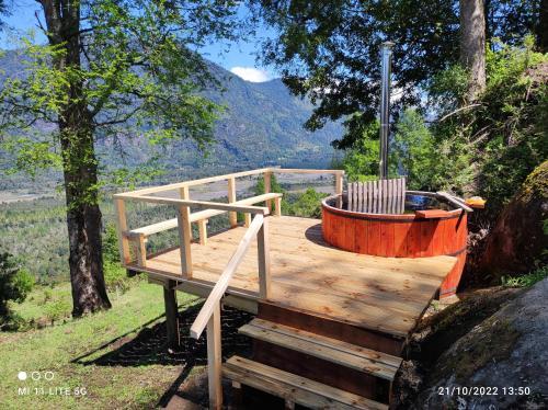 a wooden deck with a hot tub in the woods at cabaña vista nilahue in Ranco