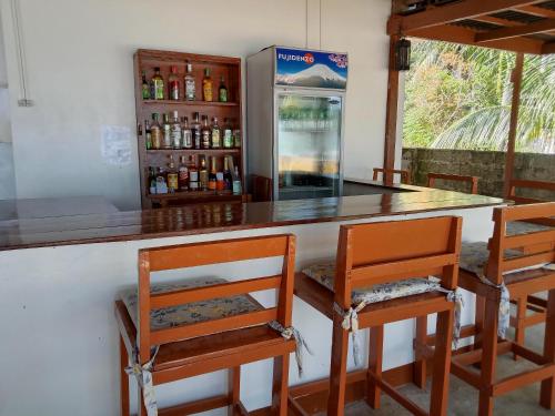 um bar com 4 cadeiras e um frigorífico em Bucana beachfront guesthouse em El Nido