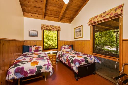 1 Schlafzimmer mit 2 Betten und 2 Fenstern in der Unterkunft Falls Lodge - a Blue Mountains experience in Wentworth Falls