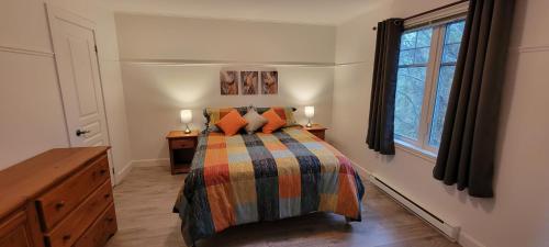 1 dormitorio con 1 cama con almohadas de color naranja y ventana en Condo Lac Archambault 305 en Saint-Donat-de-Montcalm