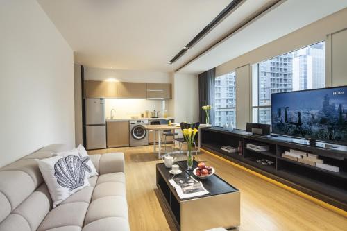 a living room with a white couch and a large tv at Citadines South Chengdu in Chengdu