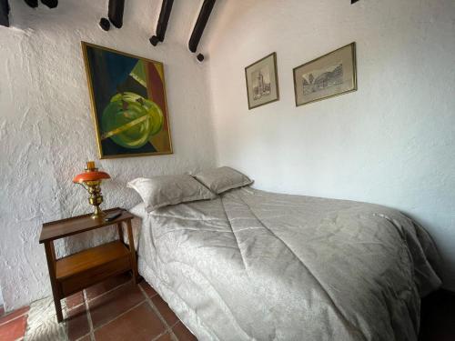 ein Schlafzimmer mit einem Bett und einem Tisch mit einer Lampe in der Unterkunft La Ronda in Guatavita