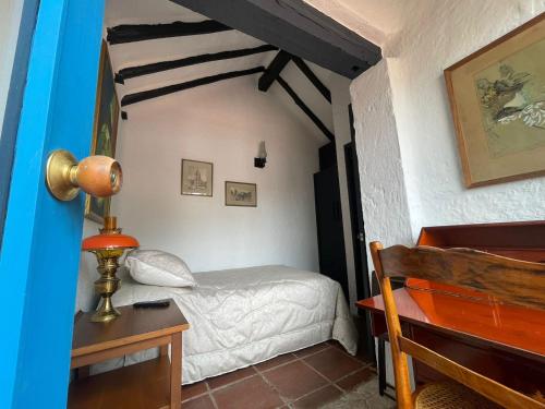 a bedroom with a bed and a desk with a lamp at La Ronda in Guatavita