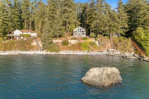 a large rock in the water in front of a house at Reef Point Retreat in La Conner