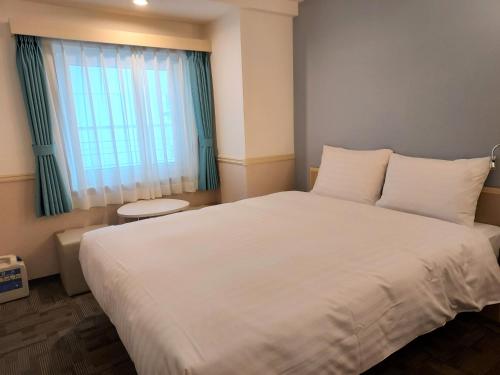 a bedroom with a large white bed and a window at Toyoko Inn Changwon in Changwon