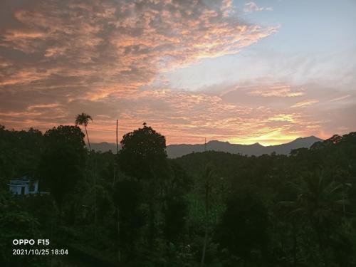 a sunset over a forest of trees and mountains at Divine View Holyday Home (Homestay) in Kalpetta