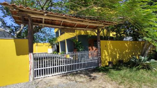 a yellow house with a white gate and a fence at Kantinho do Mar in São Francisco do Sul