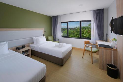 a hotel room with two beds and a desk and a window at Prime Square Hotel in Chiang Mai