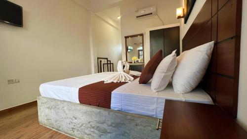 a bedroom with a large bed with white sheets and pillows at Sea Pink Residence in Bentota