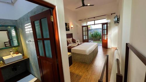 a bedroom with a bed and a bathroom with a sink at Sea Pink Residence in Bentota