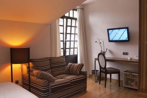 a living room with a couch and a desk and a television at Antiguo Casino Hotel in Pravia