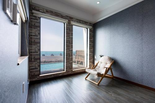 a room with a chair and a large window at Aqua Beautique Poolvilla in Jeju