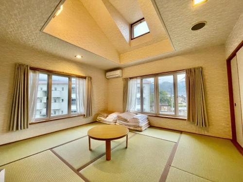 uma sala de estar com uma mesa e duas janelas em 湯布院 ソナタ Yufuin Sonata em Yufu