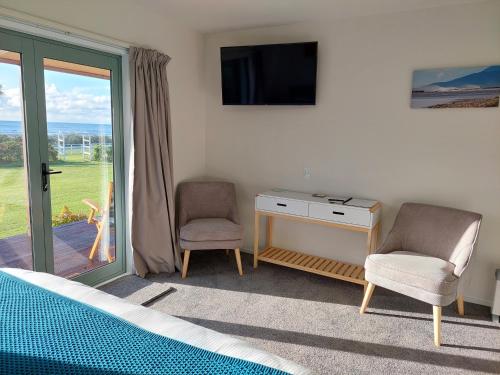 a bedroom with a television and a desk and chairs at Awatuna Sunset Lodge in Hokitika