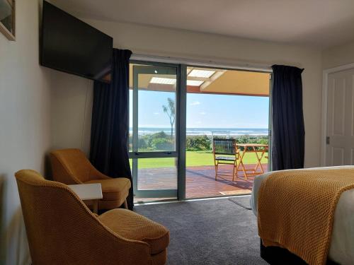 um quarto com uma cama e uma porta de vidro deslizante em Awatuna Sunset Lodge em Hokitika