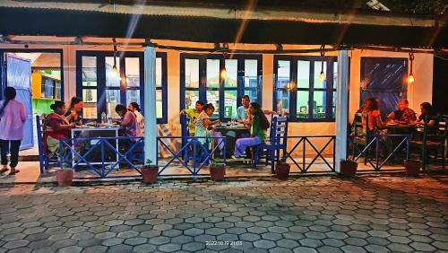 a group of people sitting at tables in a restaurant at Hotel Butterfly - Peaceful Garden for Nature Lovers in Sauraha