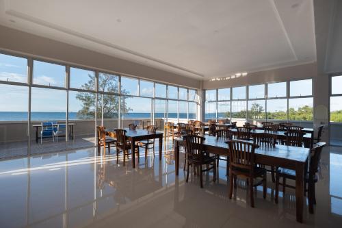 a restaurant with tables and chairs and a view of the ocean at Kelayang Beach Hotel in Tanjungbinga