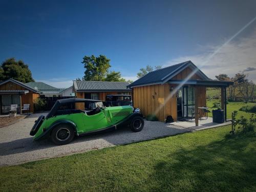 a green car parked in front of a house at Cheviot Motels, Cabins and Camp in Cheviot