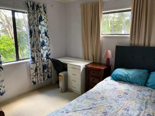 1 dormitorio con 1 cama, escritorio y ventanas en Bush , birds and relaxing moments en Auckland