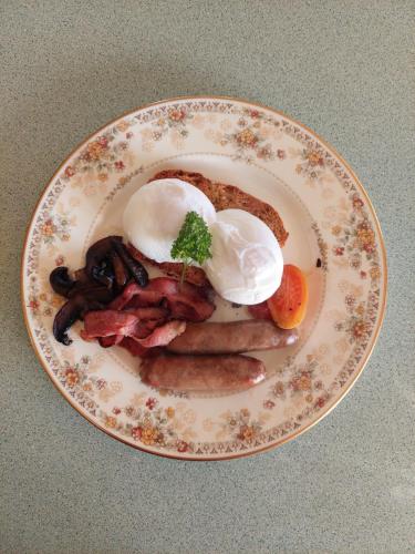 a plate of breakfast food with eggs and sausage at Awatuna Sunset Lodge in Hokitika