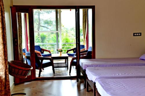 a room with two beds and a table and a window at Estate Flora Homestay - Balcony, Home Food, Coffee Estate in Sakleshpur