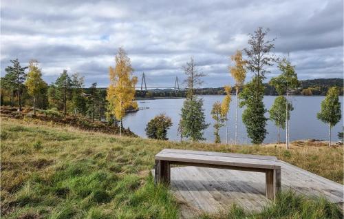 a wooden bench sitting on a field next to a lake at 3 Bedroom Lovely Home In Uddevalla in Uddevalla