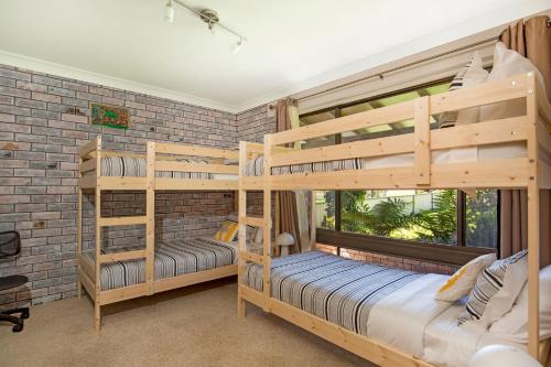 two bunk beds in a room with a brick wall at Enchante` - Pet Friendly - Absolute Waterfront - Fireplace in Culburra Beach