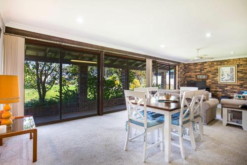 a living room with a table and chairs at Enchante` - Pet Friendly - Absolute Waterfront - Fireplace in Culburra Beach