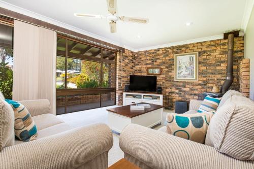 a living room with two chairs and a television at Enchante` - Pet Friendly - Absolute Waterfront - Fireplace in Culburra Beach