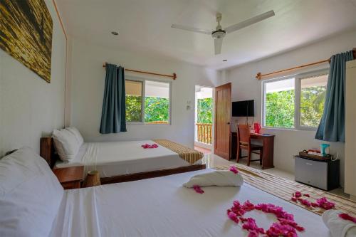 1 dormitorio con 2 camas y flores en el suelo en Evolution Dive and Beach Resort, en Isla de Malapascua