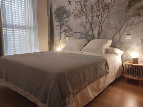 a bedroom with a large bed with a tree mural at Cordón 4- 1D VUT 09-402 in Burgos