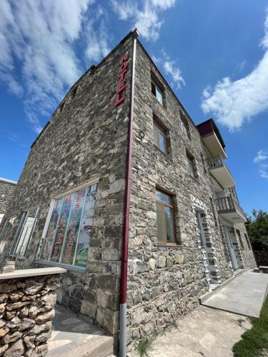 a stone building with a red sign on it at Liga Hotel and Restaurant in Shinuhayr