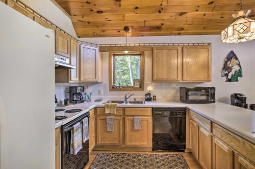 a kitchen with wooden cabinets and a sink at Elcho Escape with Private Dock on Post Lake! in Elcho