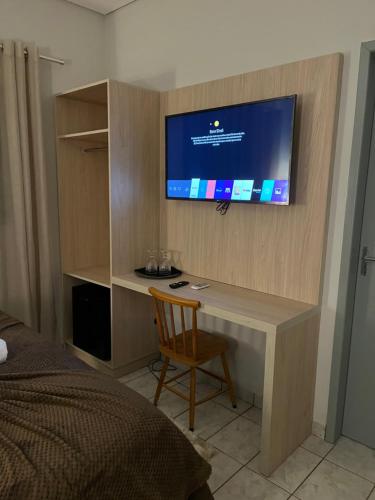 a bedroom with a desk with a television on a wall at POUSADA ACONCHEGO MT in Chapada dos Guimarães