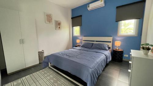 ein blaues Schlafzimmer mit einem Bett und zwei Lampen in der Unterkunft Happy House in Cha-am