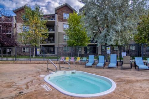 a hot tub in a courtyard with chairs and a building at Copper Suite Family Friendly 2 Bed with Amenities in Invermere