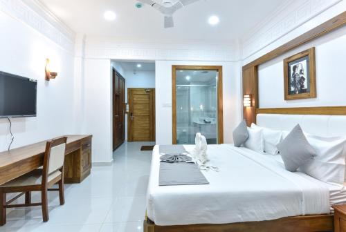 a bedroom with a bed and a desk and a television at HOTEL WHITE HOUSE, Munnar in Munnar
