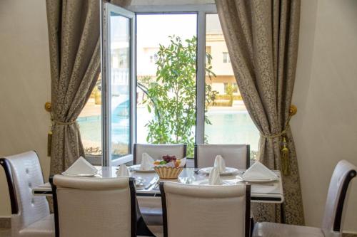 Al Salam Grand Hotel في البريمي: غرفة طعام مع طاولة وكراسي ونافذة
