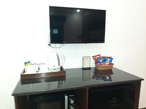 a desk with a tv on a wall with a microwave at Lawrence View Hotel, Lahore in Lahore