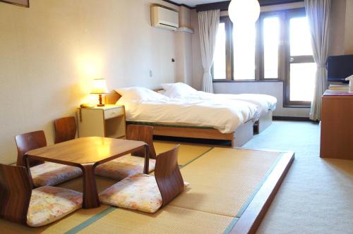 白馬村にあるプチホテル志鷹のベッド2台、テーブルと椅子が備わるホテルルームです。