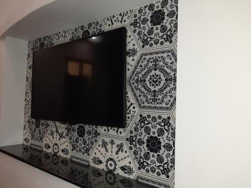 a tv on a wall with black and white tiles at Lawrence View Hotel, Lahore in Lahore