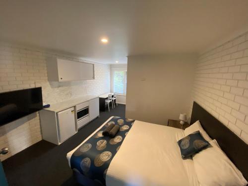 a hotel room with a bed and a flat screen tv at Southern Ocean Motor Inn in Port Campbell