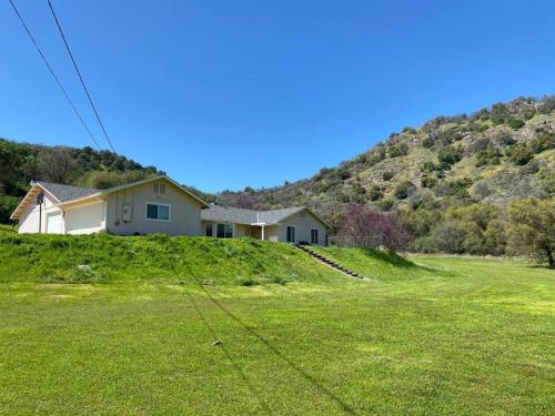 a house on the side of a hill with a green field at Waxberry Getaway Sequoia/Kings Canyon National Pks in Squaw Valley