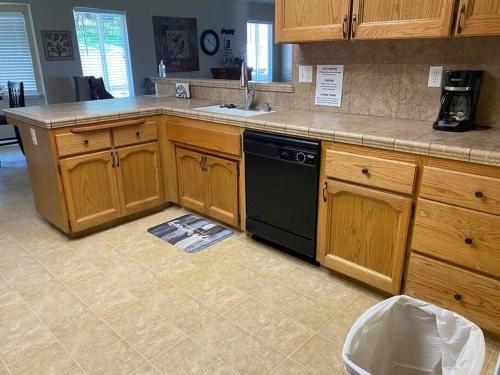 a kitchen with wooden cabinets and a black dishwasher at Waxberry Getaway Sequoia/Kings Canyon National Pks in Squaw Valley