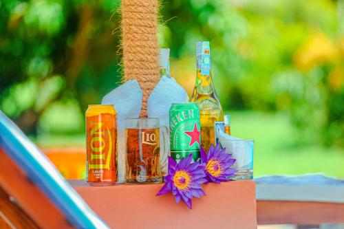 a table with bottles of beer and flowers on it at Sigiriya Water Cottage in Sigiriya