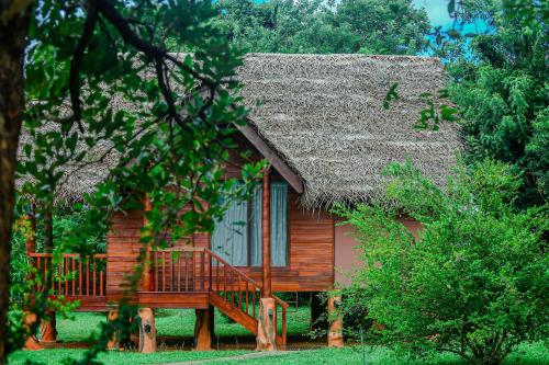 a small wooden house with a thatch roof at Sigiriya Water Cottage in Sigiriya