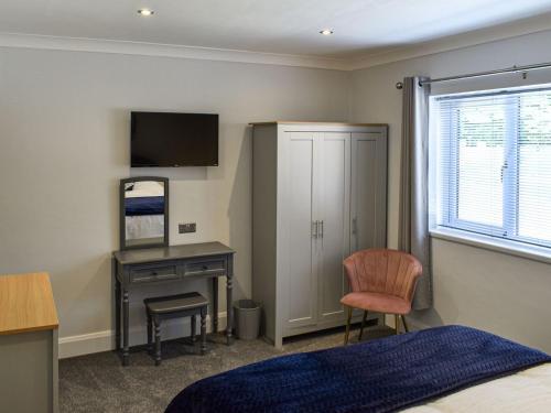 a bedroom with a bed and a desk with a computer at Grange Garth Cottage in Acaster Malbis